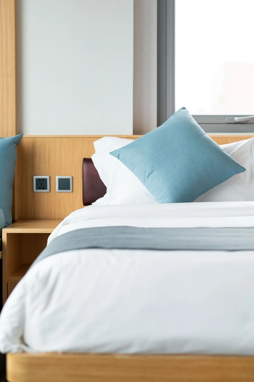 Blue cushion and crisp white bedding in the Corner Twin Room at Greenery Inn, Macau